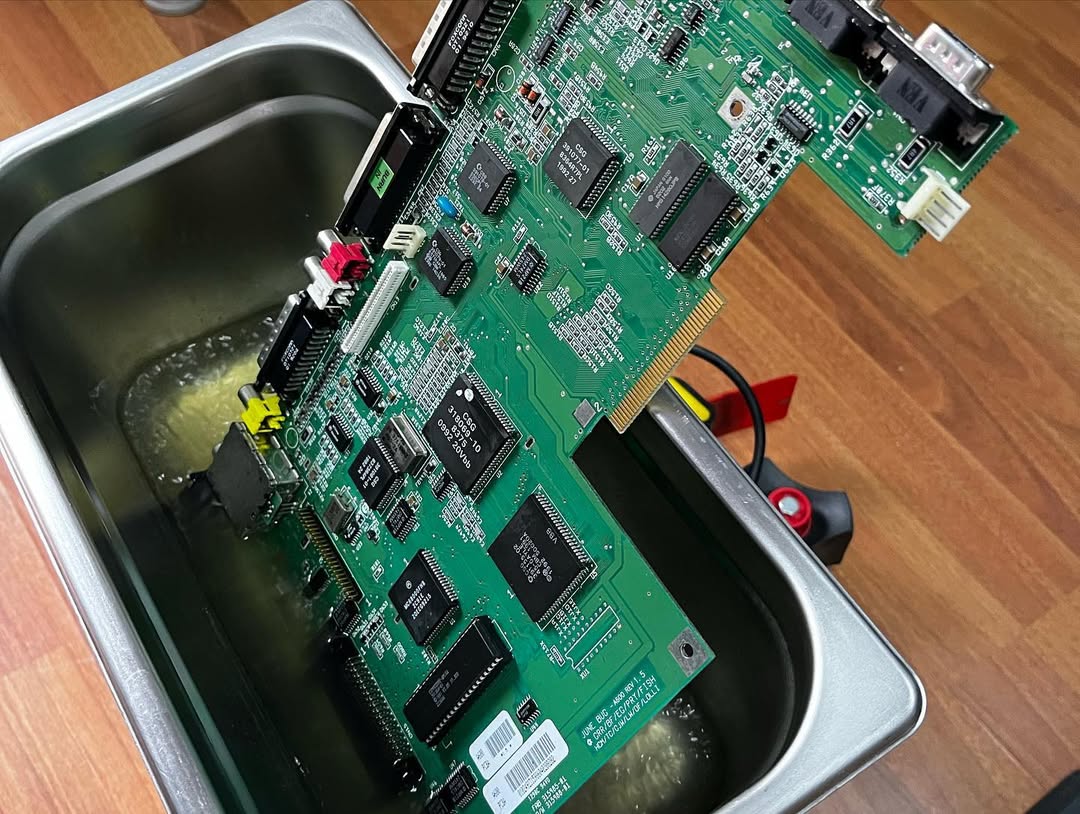 Scheda madre Amiga 600 immersa in lavatrice a ultrasuoni per pulizia profonda post-riparazione